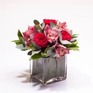 ARRANJO DE ROSAS VERMELHAS E ORQUÍDEA CYMBIDIUM EM CUBO DE VIDRO